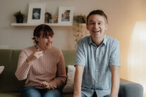 Zwei Bewohner:innen sitzen auf dem Sofa und lachen