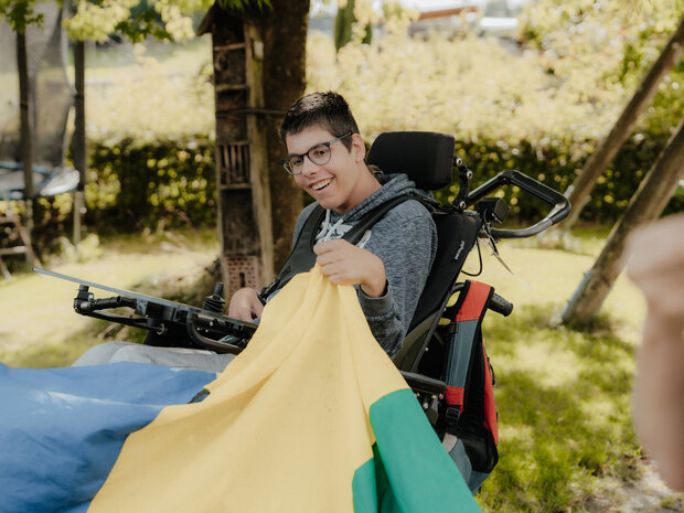 Menschen spielen mit einem bunten Tuh im Garten