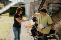 Zwei Frauen bei der Befüllung von Hühner-Futter-Spender-Boxen